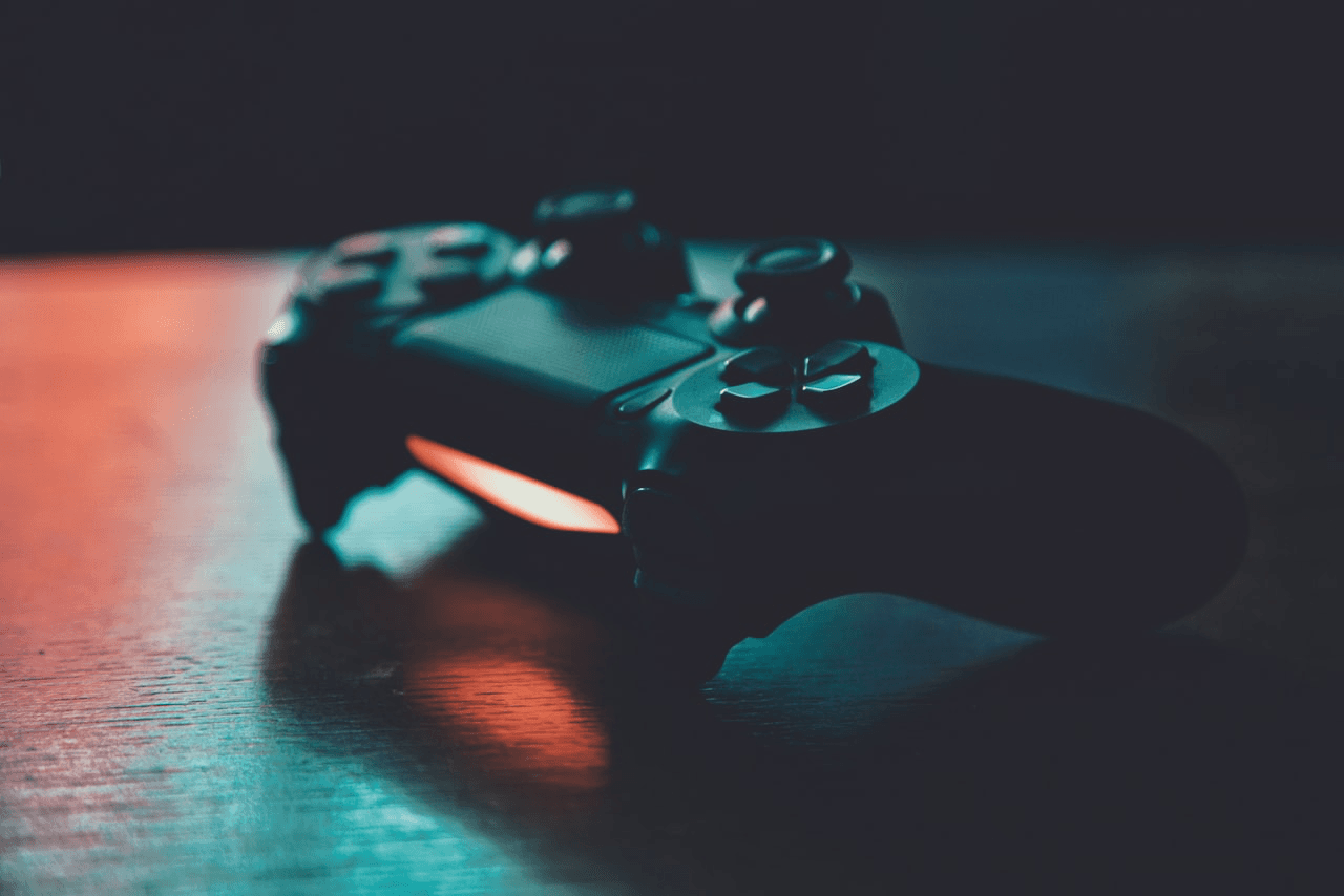A gaming controller on a dark surface lit by red and blue neon light