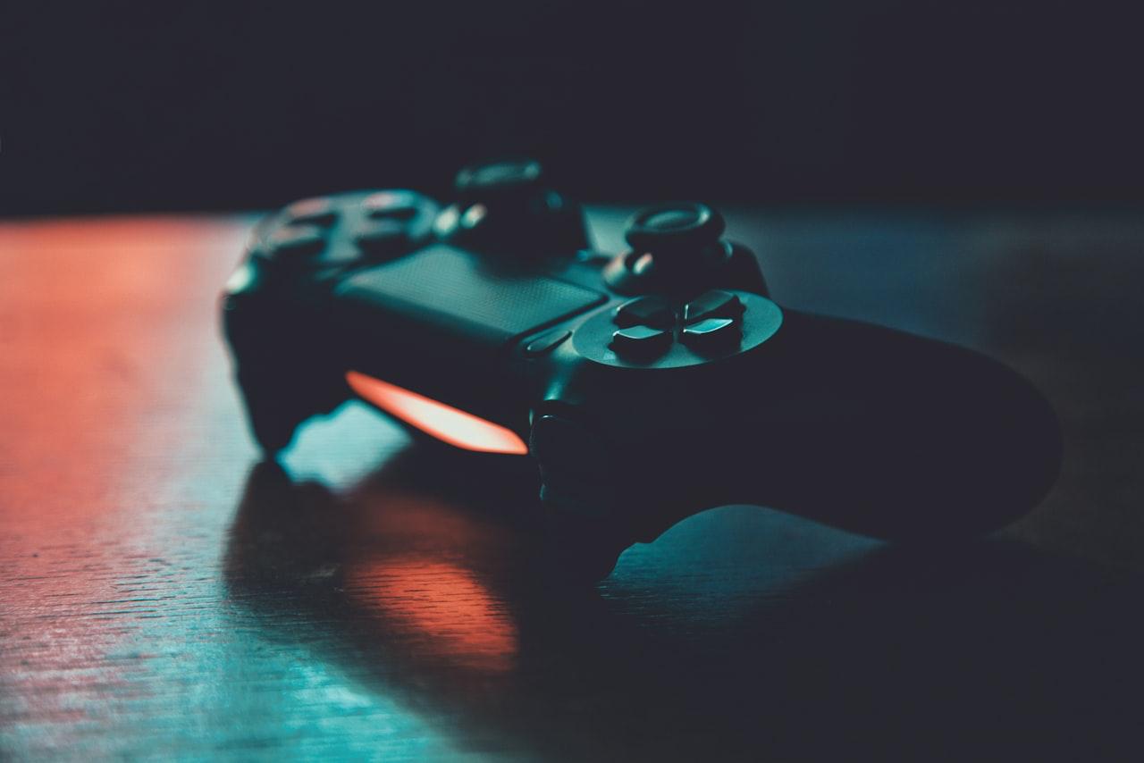 A gaming controller on a dark surface lit by red and blue neon light