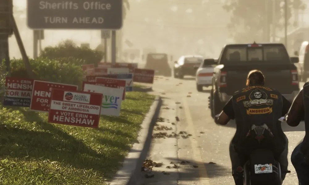 Close-up of election yard signs in GTA 6's Ambrosia: 'Erin Henshaw for Mayor' signs and an Allied Crystal sign reading 'The Sweet Lifeblood of Ambrosia, Vote Erin Henshaw', beside an Ambrosia County Sheriffs Office sign