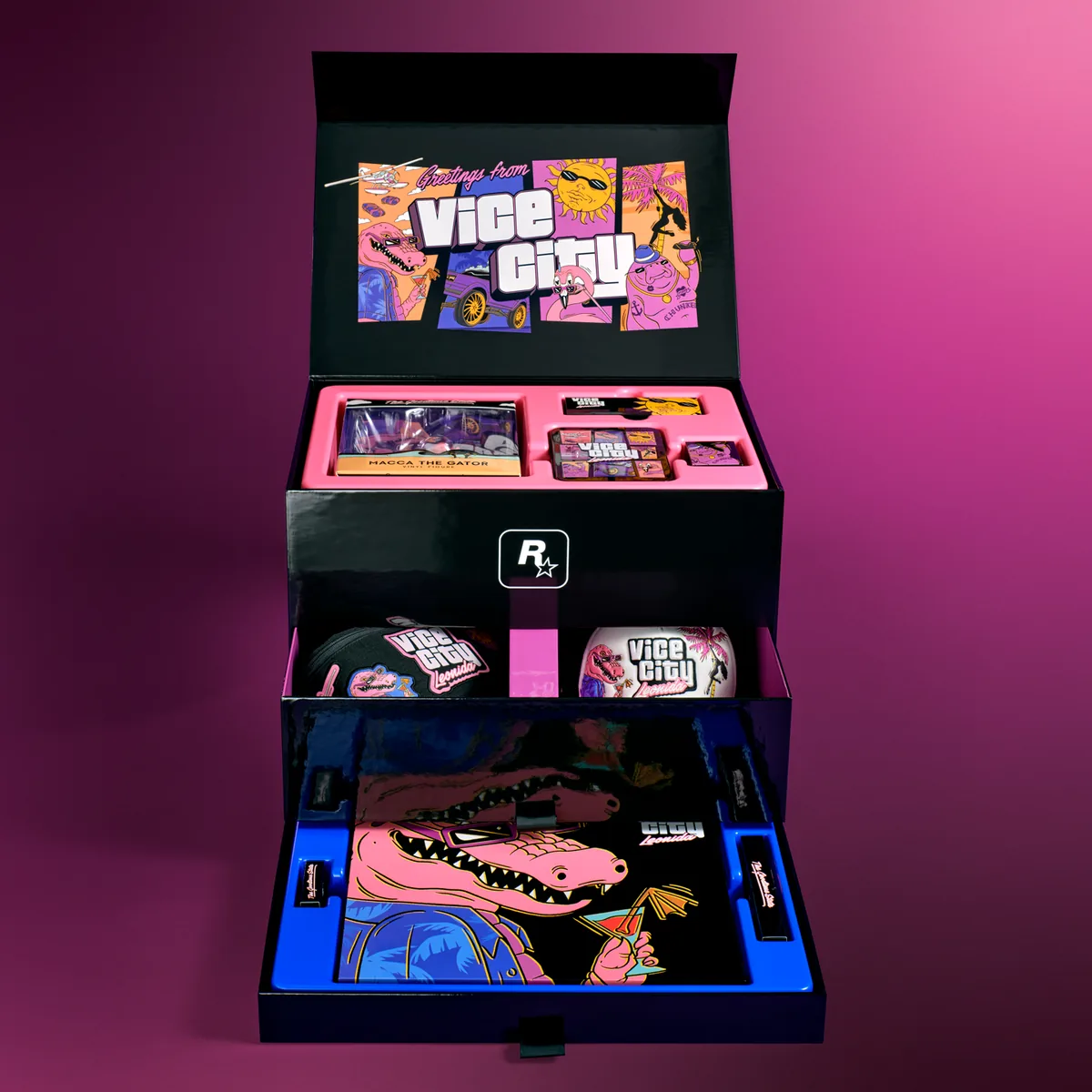 The GTA 6 Vice City Collection box open, with Greetings from Vice City artwork inside the lid, a tray holding the Macca the Gator figure, and drawers with the hat, mirror and poster
