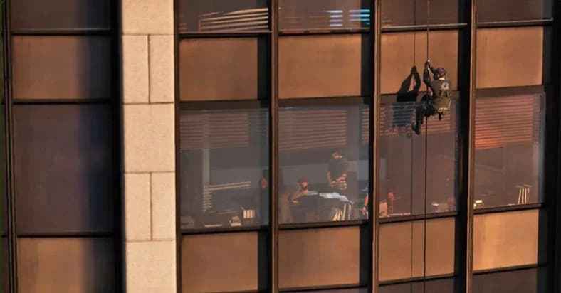 Michael rappelling down the glass facade of the IAA headquarters in GTA 5, with office workers visible inside