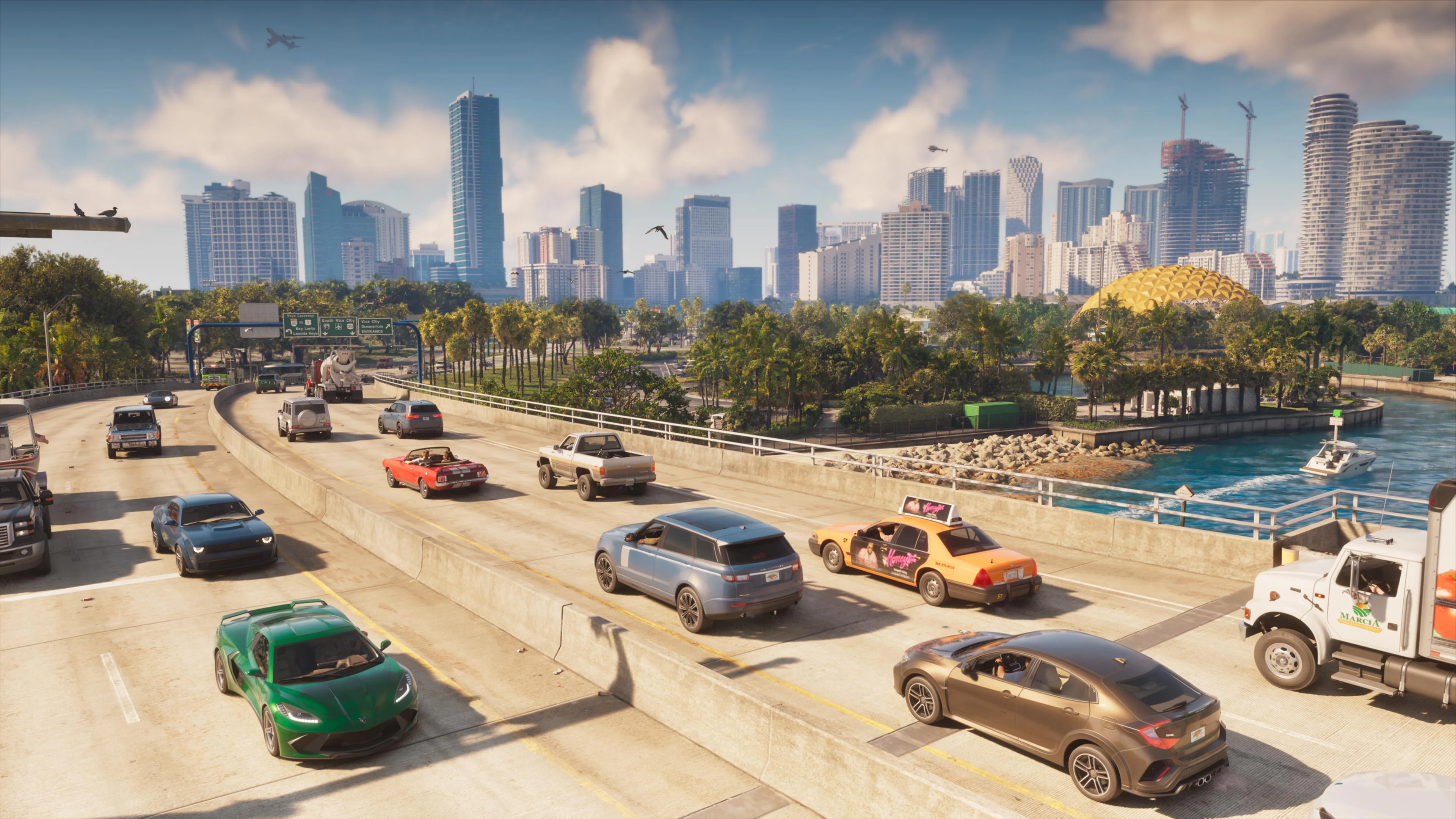 Traffic backed up on an elevated Vice City highway below the downtown skyline, with a taxi, a delivery truck, a golden dome and a boat on the bay