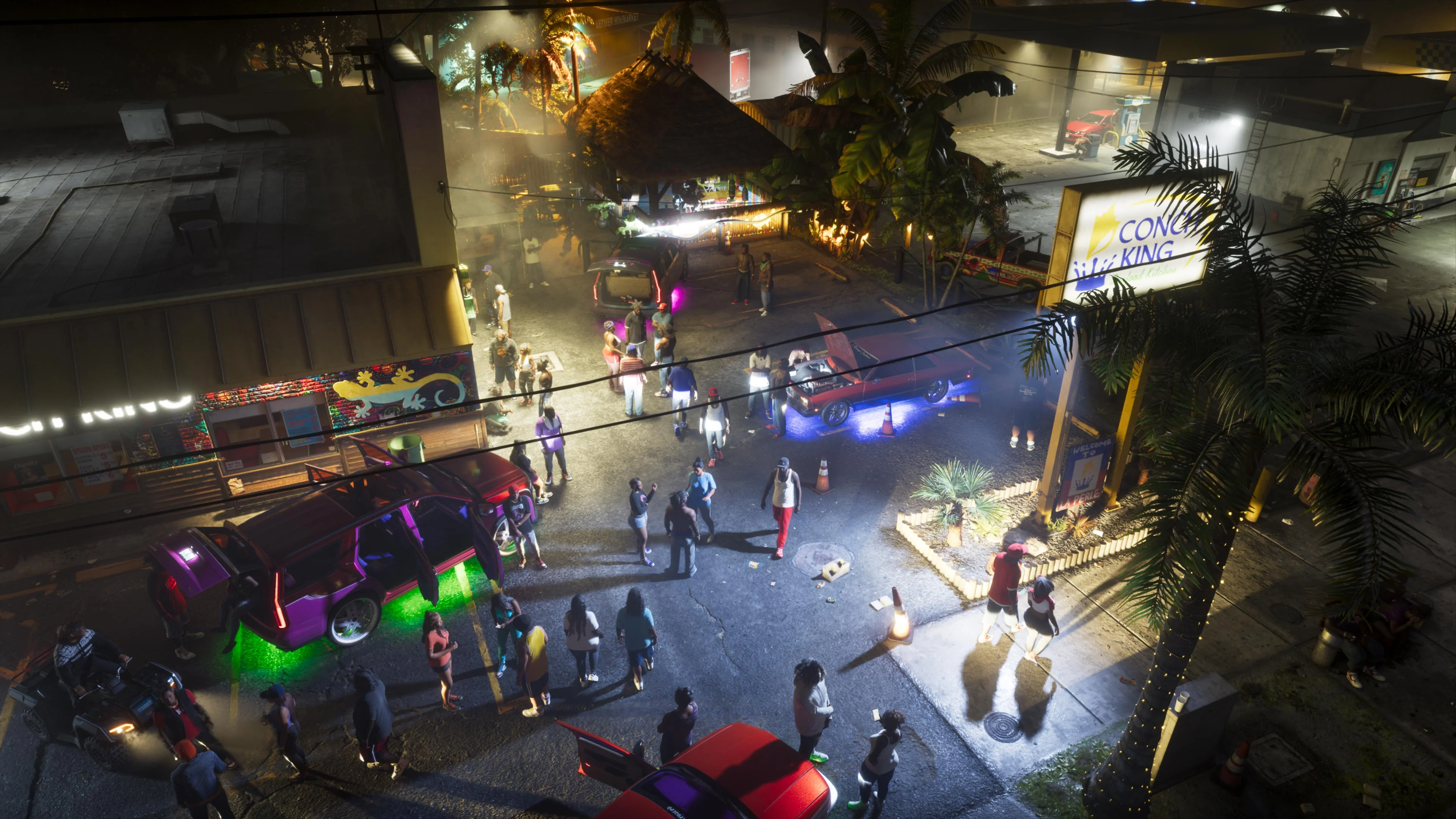 A crowded night car meet in a strip-mall parking lot, with underglow-lit cars, a thatched-roof stand and a Conch King sign